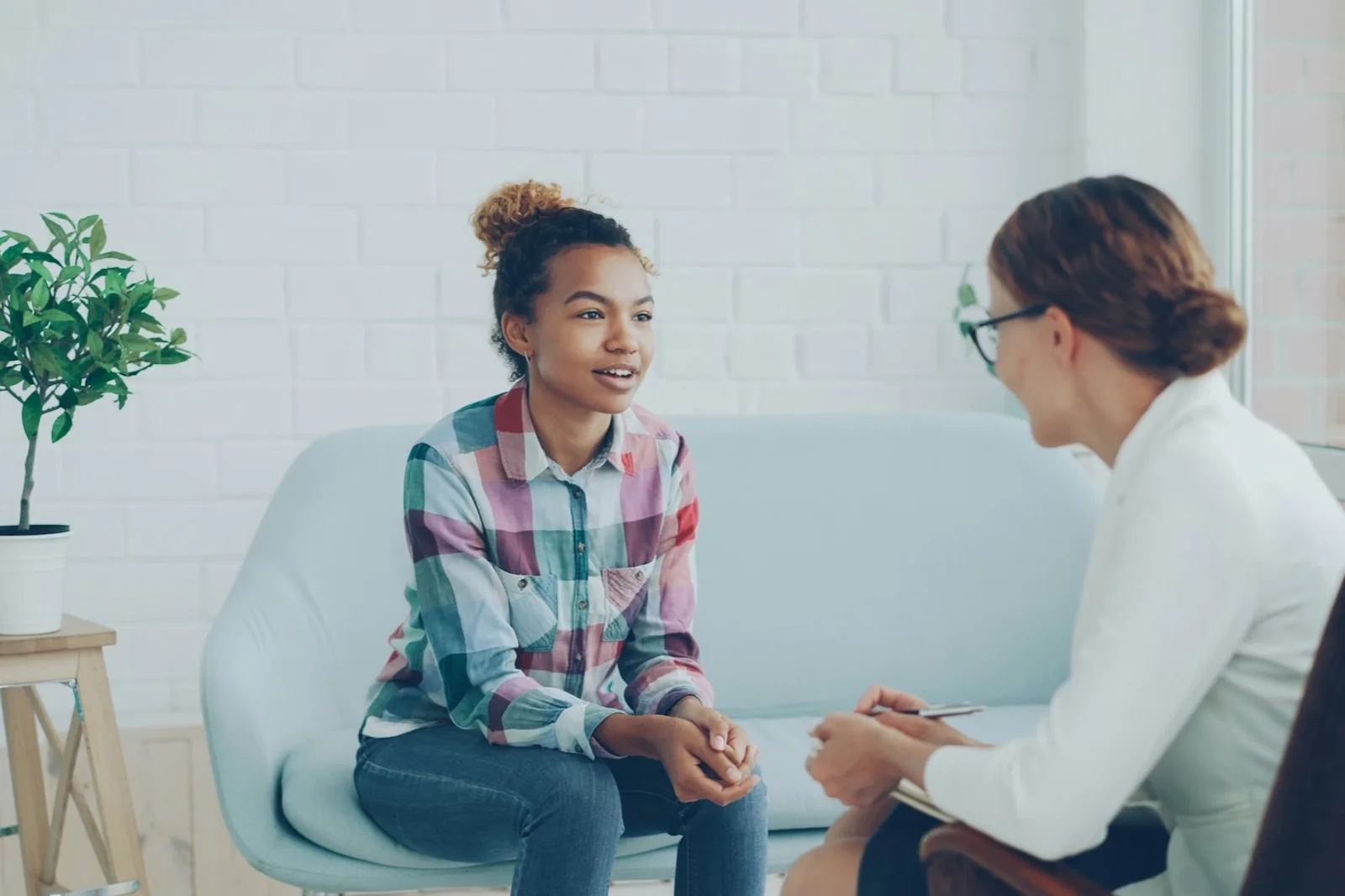 Two women talking in a bright, plant-filled room