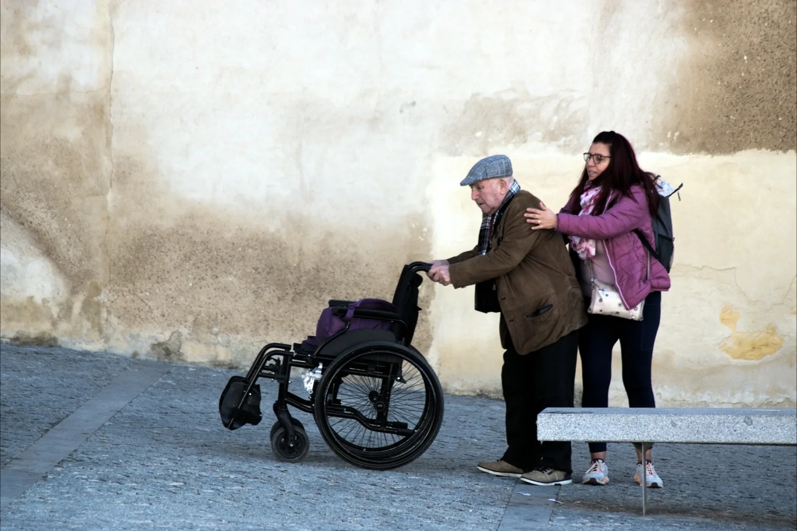 Two people walking along a footpath with a wheelchair