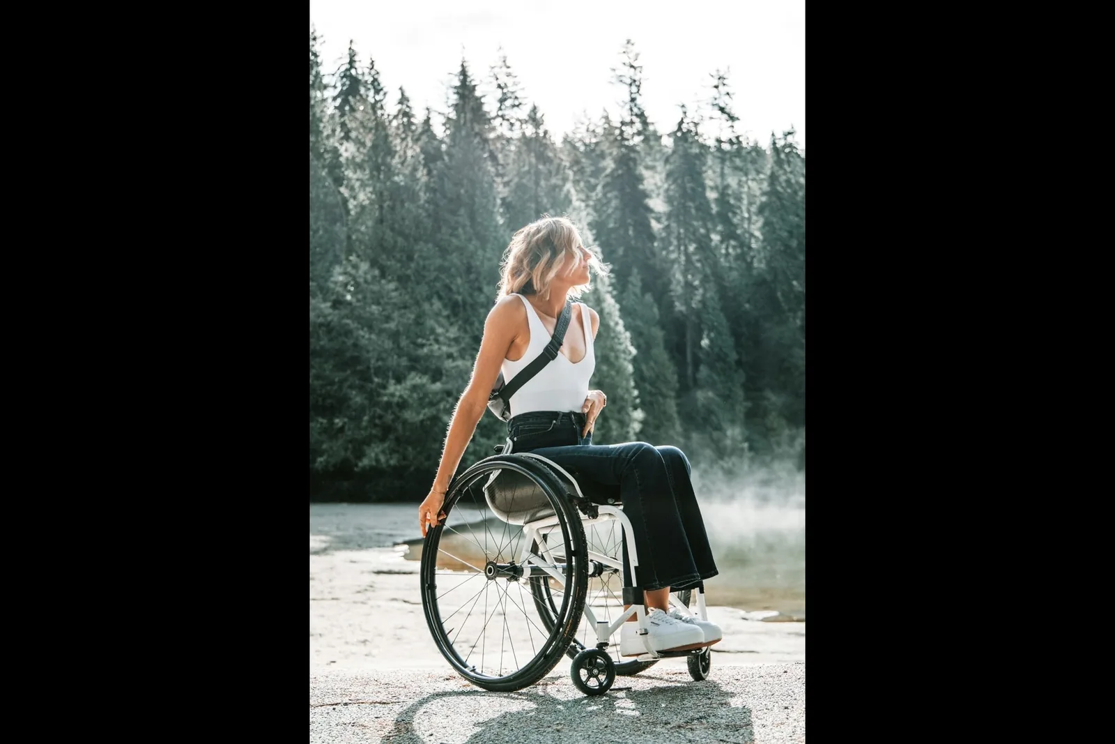 A woman in a wheelchair on a path through a pine forest